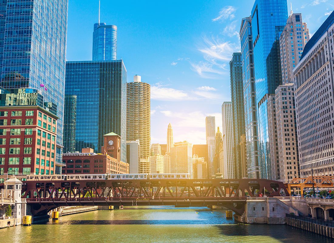 Schaumburg, IL - View of Skyscrapers on Both Sides of the River with a Bridge and Subway Going Across in the City of Chicago on a Sunny Day