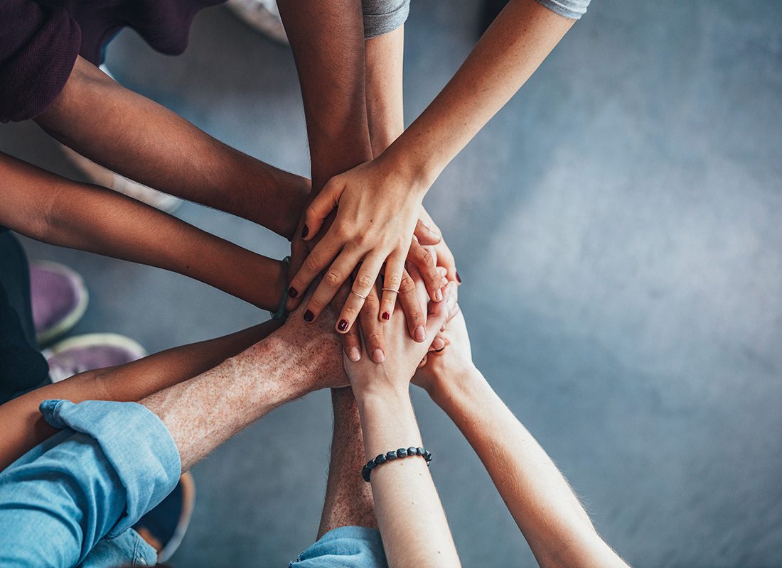 Community Involvement - Closeup View of a Small Group of People Stacking Their Hands Together During a Community Volunteer Event